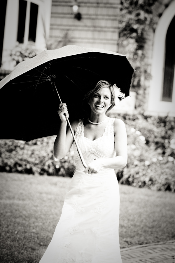 Black and white photo - The beautiful bride wearing a white an a-line style dress and holding an umbrella - photo by North Carolina based wedding photographer Jeremie Barlow